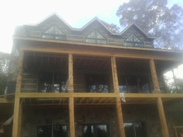 Dormers and porch framing on a large log home under construction — Roof Coating work by our crew in Beallsville