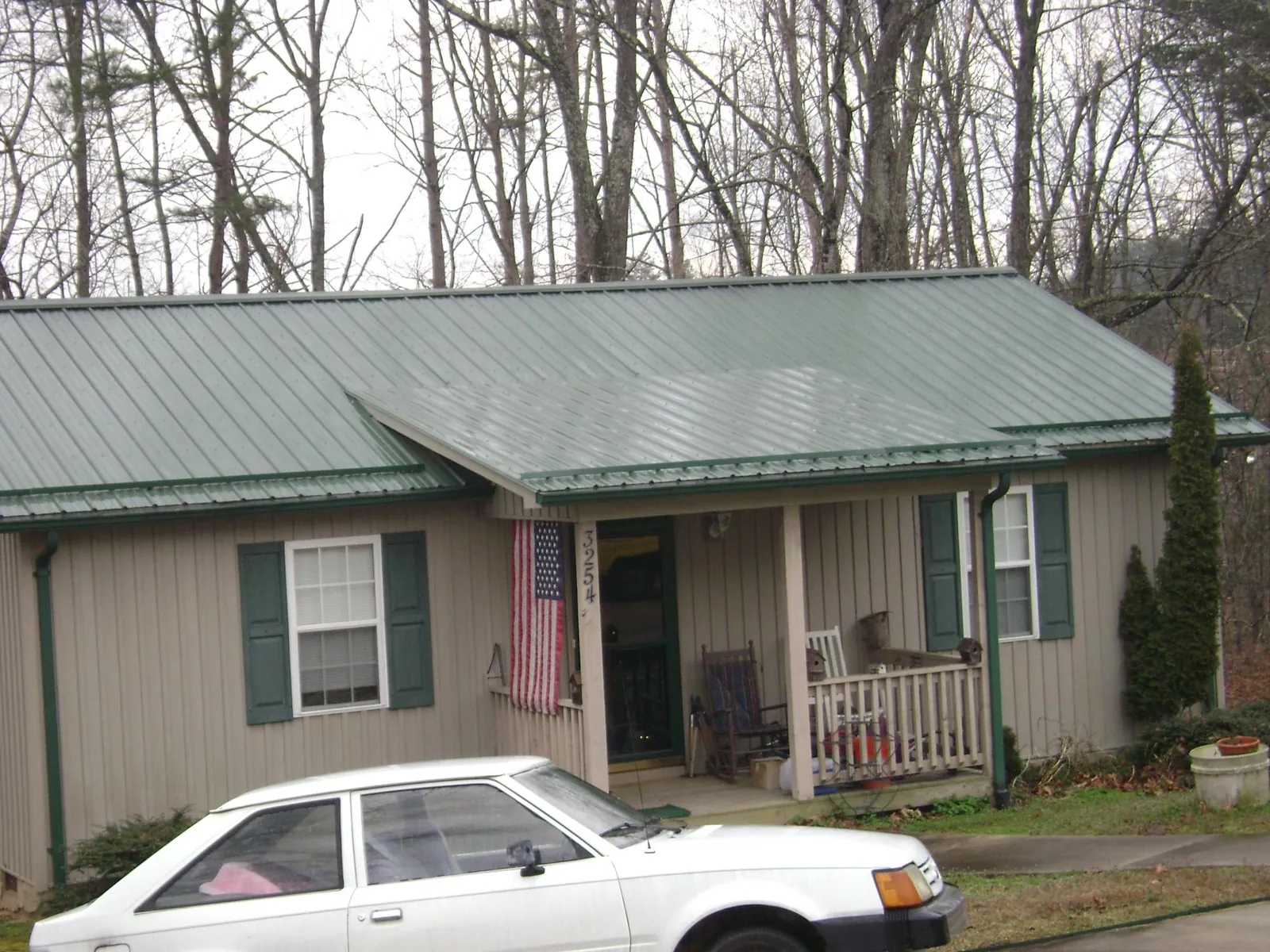 Green metal roof and front porch on a tan sided cottage in Beallsville